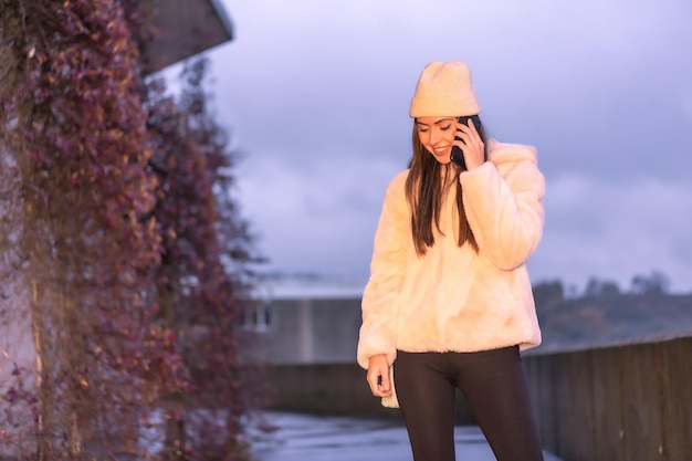 Jonge mooie blanke brunette die in de winter door de stad loopt en een roze wollen trui draagt