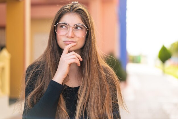 Jonge mooie blanke vrouw met een bril en twijfels.