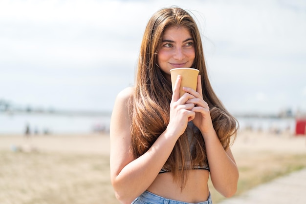 Jonge mooie blanke vrouw met een koffie om mee te nemen.