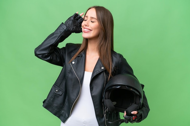 Jonge mooie blanke vrouw met een motorhelm over geïsoleerde achtergrond die veel glimlacht