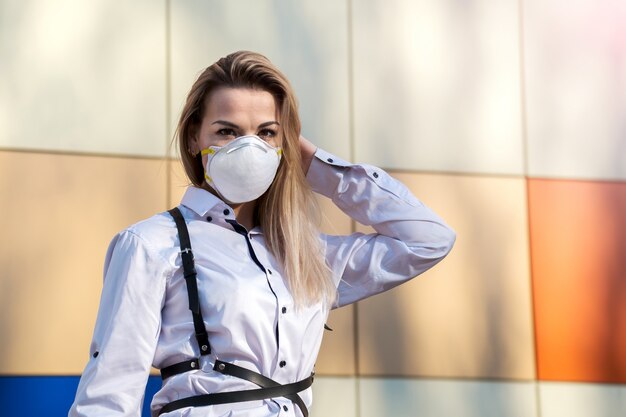 Jonge mooie blonde blanke vrouw permanent in een beschermend masker buitenshuis,