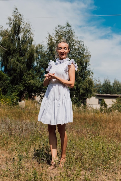 Jonge mooie blonde in een rustieke jurk staat in het veld