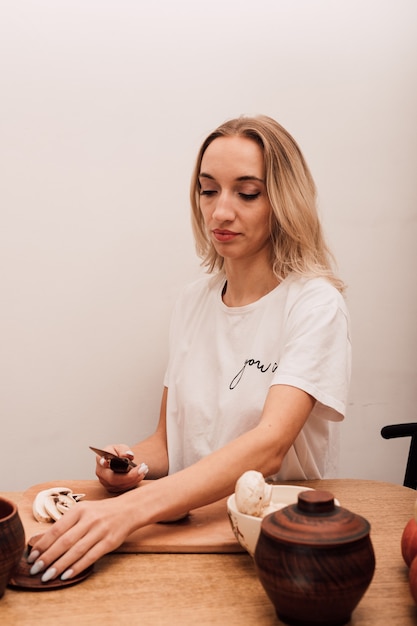 Jonge mooie blonde snijdt champignons op tafel in de keuken