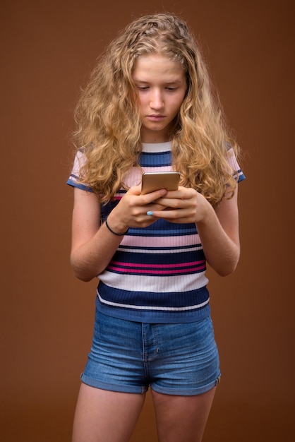 Jonge mooie blonde tiener texting met mobiele telefoon