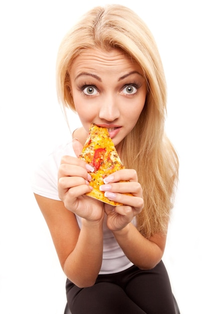 Jonge mooie blonde vrouw die een stuk pizza eet