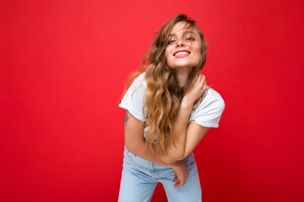 Jonge, mooie blonde vrouw die een wit t-shirt draagt en naar een camera kijkt, toont een positieve vrouw met een gezichtsbehandeling