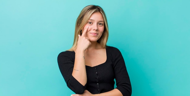 Foto jonge mooie blonde vrouw die je in de gaten houdt, niet vertrouwt op het kijken en alert en waakzaam blijft