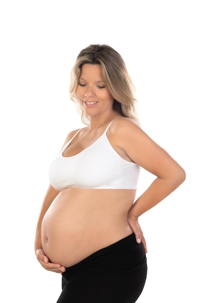 Jonge, mooie blonde vrouw die zwanger is en een baby verwacht over een geïsoleerde witte achtergrond met een vrolijke en koele glimlach op het gezicht