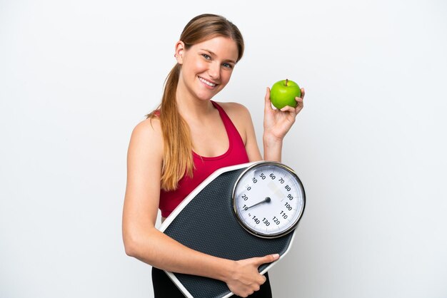 Jonge mooie blonde vrouw geïsoleerd op een witte achtergrond met weegmachine en met een apple