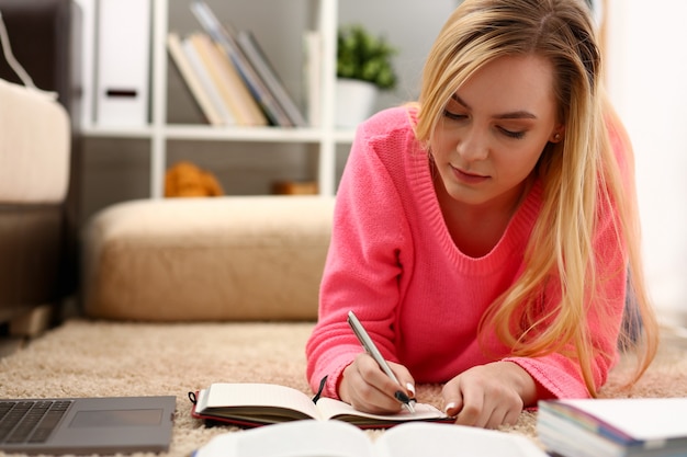 Jonge mooie blonde vrouw ligt op de vloer lees boek