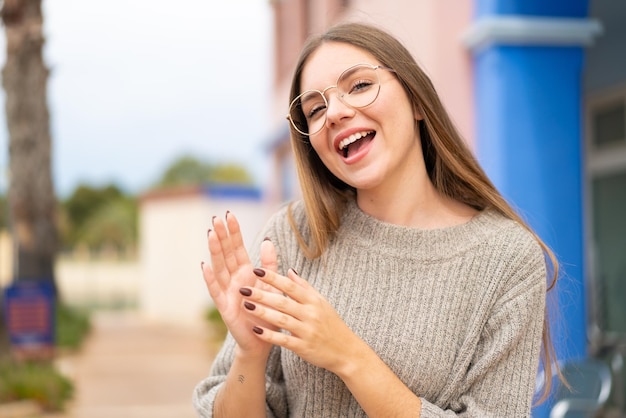 Jonge mooie blonde vrouw met bril en applaudisseren