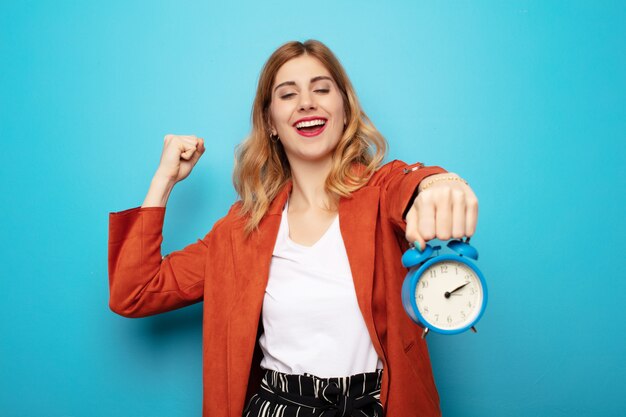 Jonge mooie blonde vrouw met een wekker