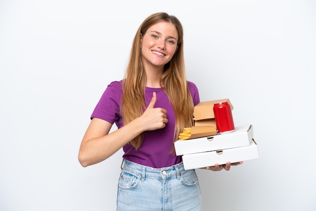 Jonge mooie blonde vrouw met fastfood geïsoleerd op een witte achtergrond met een duim omhoog gebaar