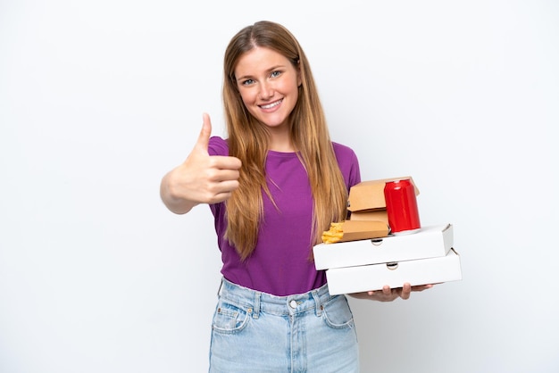 Jonge mooie blonde vrouw met fastfood geïsoleerd op een witte achtergrond met thumbs up omdat er iets goeds is gebeurd