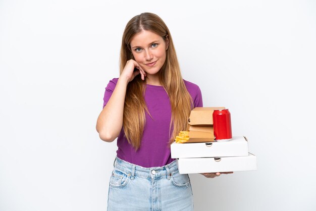 Jonge mooie blonde vrouw met fastfood geïsoleerd op witte achtergrond lachen