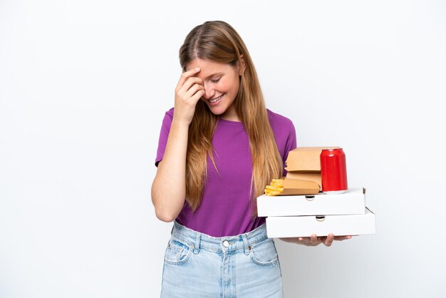 Jonge mooie blonde vrouw met fastfood geïsoleerd op witte achtergrond lachen