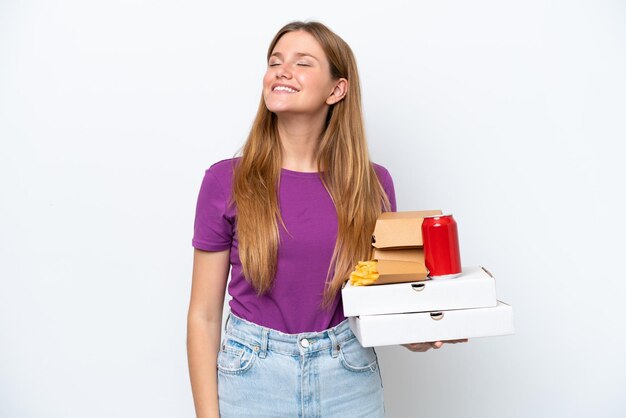 Jonge mooie blonde vrouw met fastfood geïsoleerd op witte achtergrond lachen