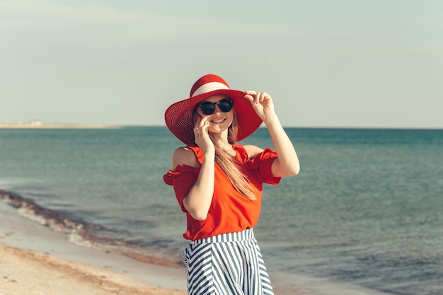 Jonge mooie blonde vrouw met mobiel op het strand