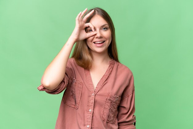 Jonge mooie blonde vrouw op een geïsoleerde achtergrond met een ok-teken met haar vingers.