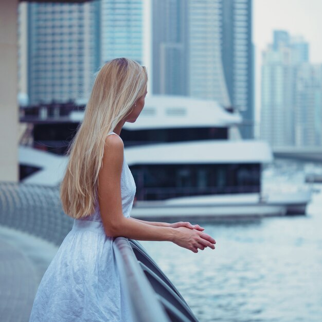 Jonge mooie blonde vrouw portret in Dubai Marina met wolkenkrabbers