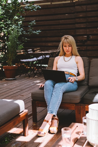 Jonge mooie blondy vrouw die op laptop werkt in een gezellige coworking space