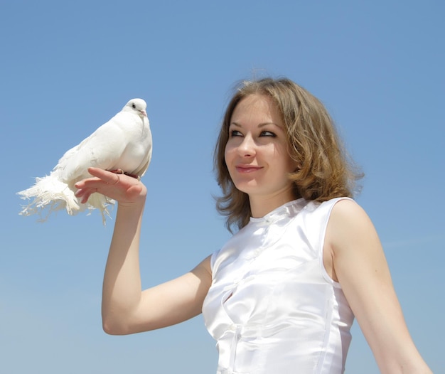 Jonge mooie bruid die een witte duif op haar hand houdt