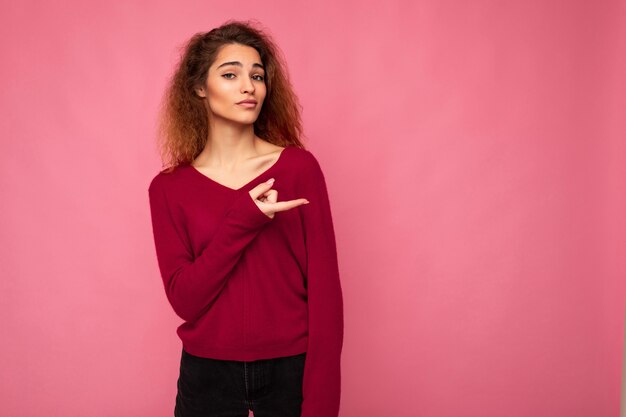 Jonge mooie brunette golvende vrouw met oprechte emoties dragen casual roze trui geïsoleerd over