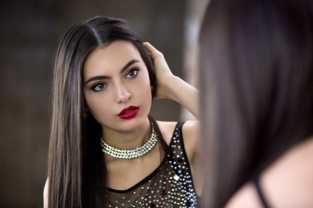 Jonge mooie brunette kijkt in de spiegel en maakt haar recht