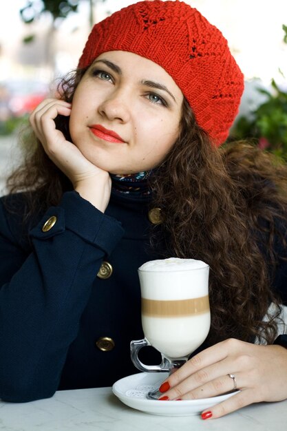 Jonge mooie brunette met een heerlijke latte in een straatcafé