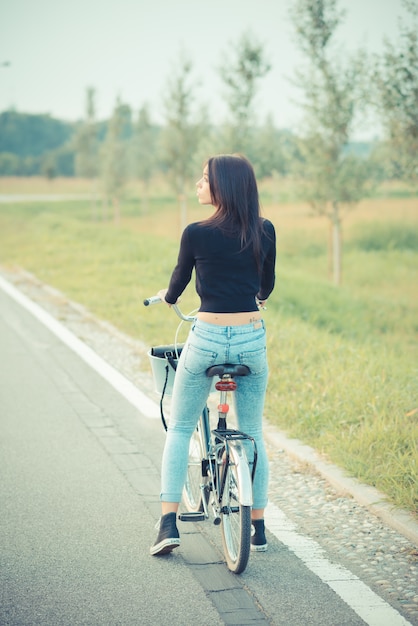 jonge mooie brunette steil haar vrouw met behulp van de fiets