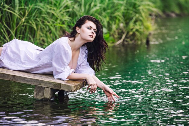 Jonge mooie brunette vrouw geniet van het meer met turkoois helder water