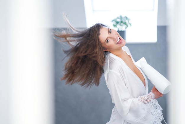 Jonge mooie brunette vrouw in de badkamer haarverzorging Foto van hoge kwaliteit