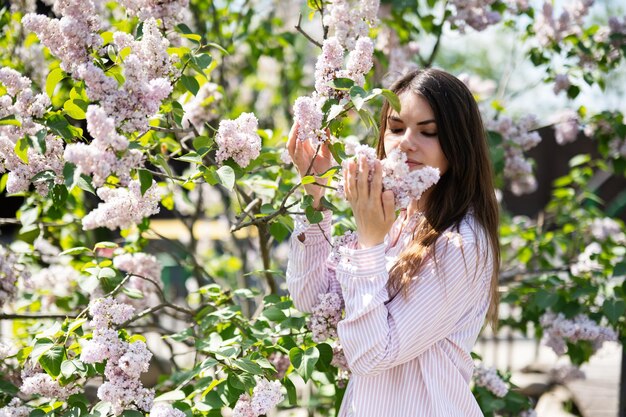 Jonge mooie brunette vrouw in shirt in de buurt van lila boom