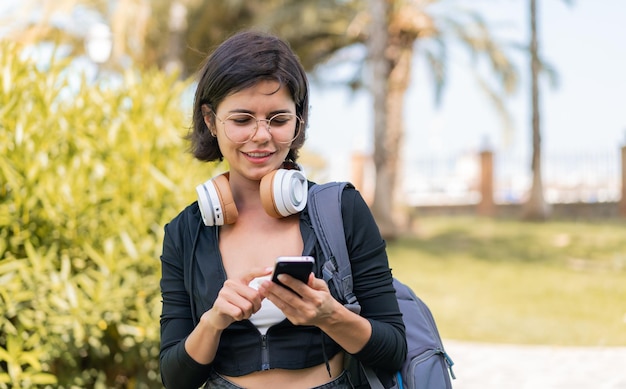 Jonge mooie Bulgaarse vrouw buitenshuis met behulp van mobiele telefoon