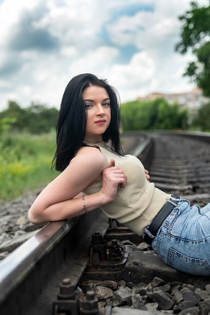 Jonge mooie dame geniet van de zomer op het treinspoor in de natuur