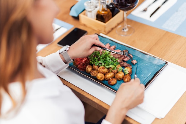 Jonge, mooie en gelukkige vrouw die geniet van een heerlijke maaltijd in een luxe restaurant.