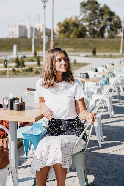 jonge mooie Europese vrouw zit in de zomer op een caféterras