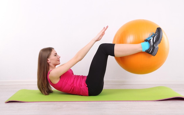 Jonge mooie fitness meisje trainen met oranje bal in de sportschool