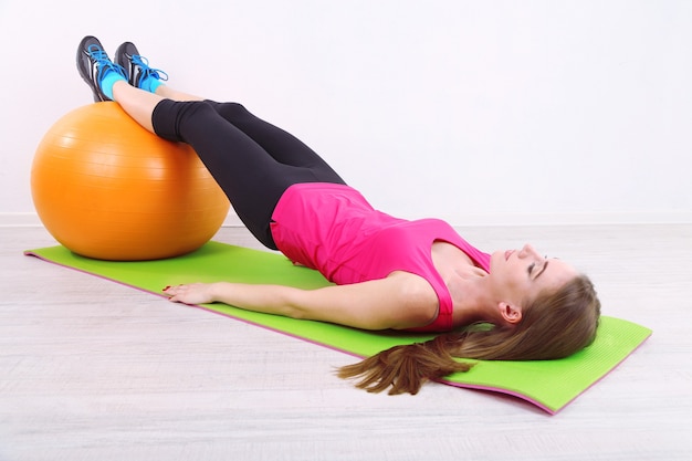 Jonge mooie fitness meisje trainen met oranje bal in sportschool