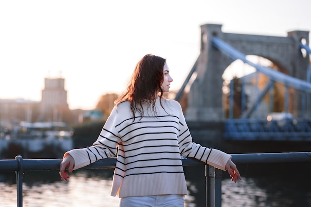 Jonge mooie glimlachende hipster vrouw in trendy zomerkleding Sexy zorgeloos model poseren op de europa straat achtergrond bij zonsondergang Positieve brunette vrouw Vrolijk en gelukkig