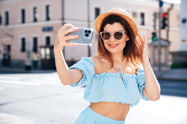 Jonge, mooie, glimlachende hipstervrouw in trendy zomerblauwe kleren buiten.