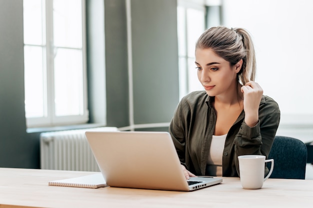 Jonge mooie glimlachende student die met vrienden op laptop babbelen.