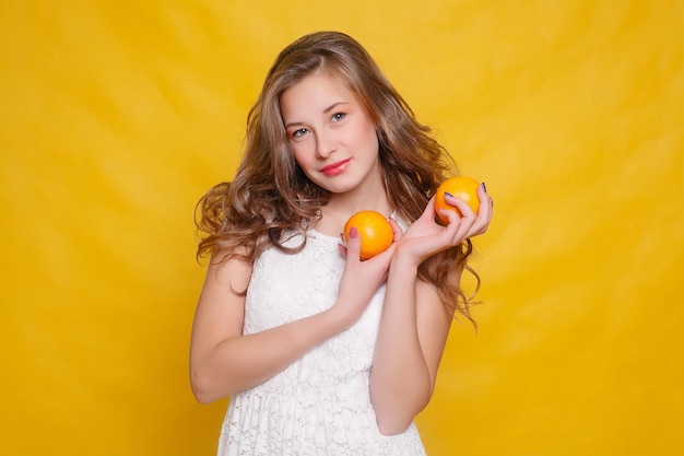 Jonge mooie grappige mannequin met sinaasappelschijfje op oranje achtergrond. met make-up en kapsel. met citroen met een mooie glimlach.
