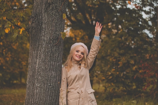 Jonge mooie herfst vrouw zwaaien zeggen hallo en glimlachen buiten vriendelijk welkom gebaar