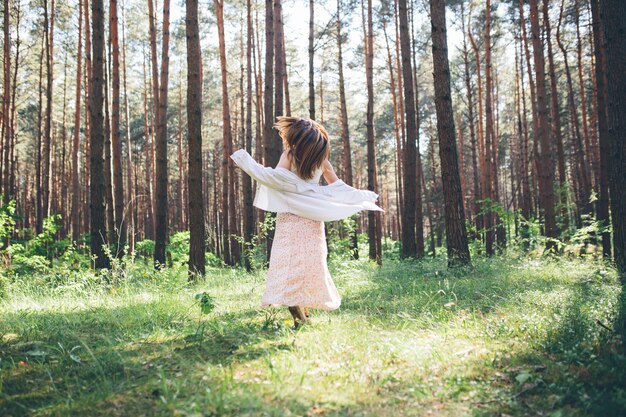 Jonge mooie hippievrouw loopt in het zomerbos, lacht danst en geniet van het leven en de natuur