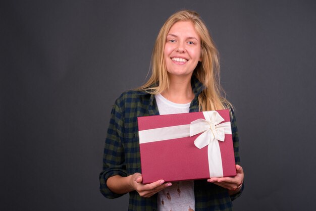 jonge mooie hipster vrouw met blond haar tegen grijze muur