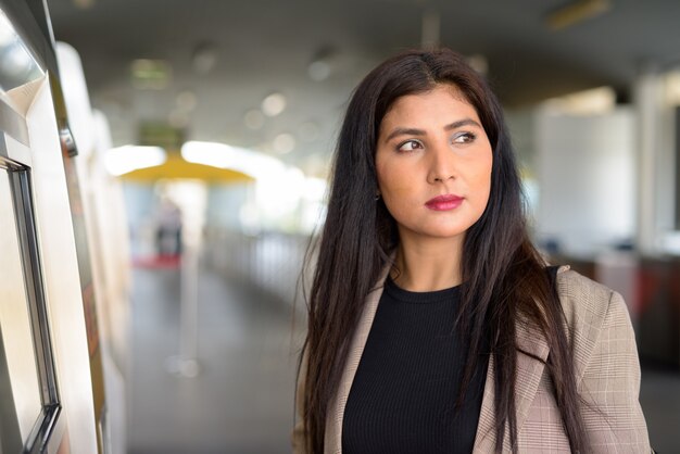 Jonge mooie Indiase zakenvrouw denken bij het skytrain-station