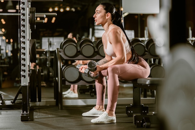 Jonge mooie Kaukasische fit sterke vrouw doet oefeningen in de sportschool