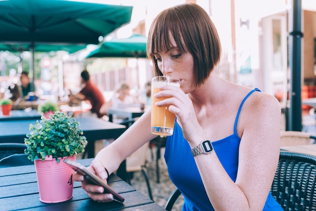 Jonge mooie Kaukasische gember hoofdvrouw die gezonde smoothie drinkt