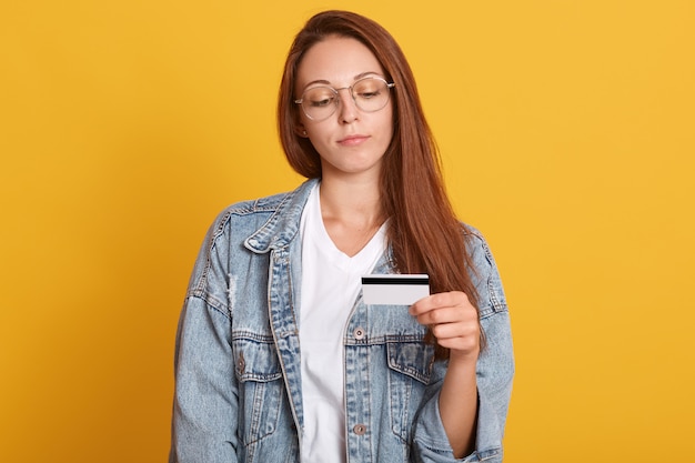 Jonge mooie Kaukasische vrouw die creditcard voor het verrichten van betaling voorstelt